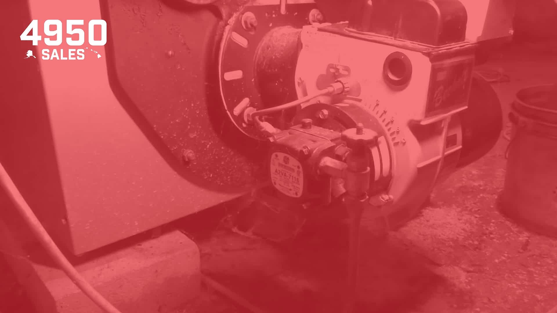 Commercial-Power-Burners-Alaska-4950-Sales-optimized - Beckett Corporation Close-up of a hydraulic valve assembly with hoses and fittings on a metal machine, red-tinted image.